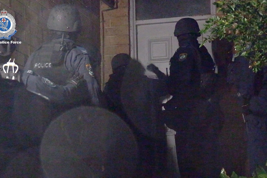police approach the door of a house at nigh time