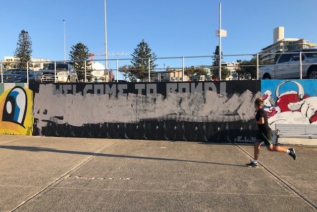 A jogger runs past the vandalised mural.