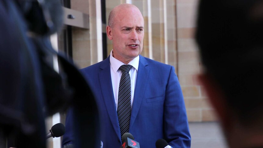 A mid shot of WA Treasurer Dean Nalder wearing a blue suit and black tie talking to reporters outside State Parliament.