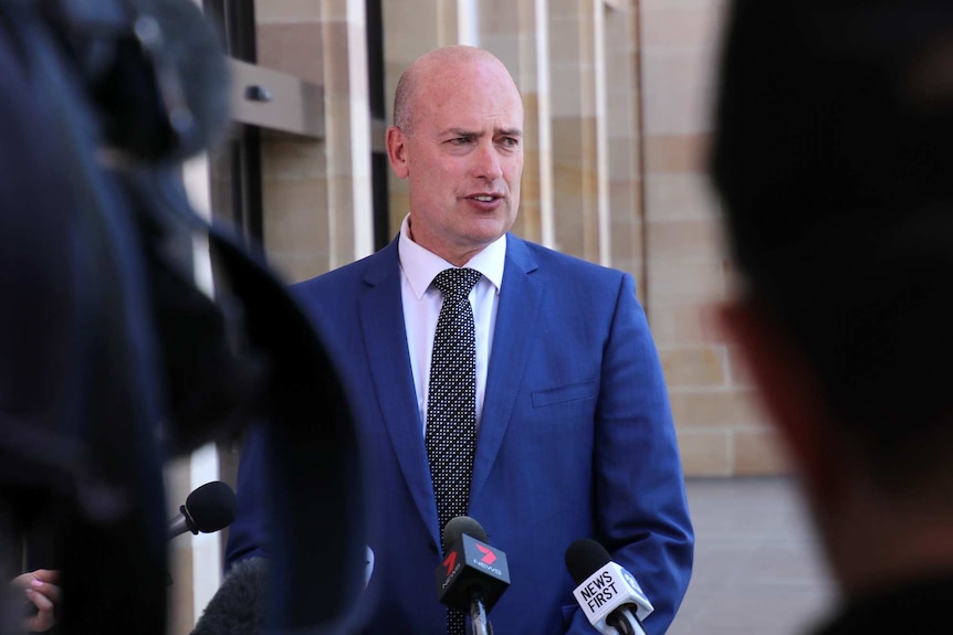 A mid shot of WA Treasurer Dean Nalder wearing a blue suit and black tie talking to reporters outside State Parliament.