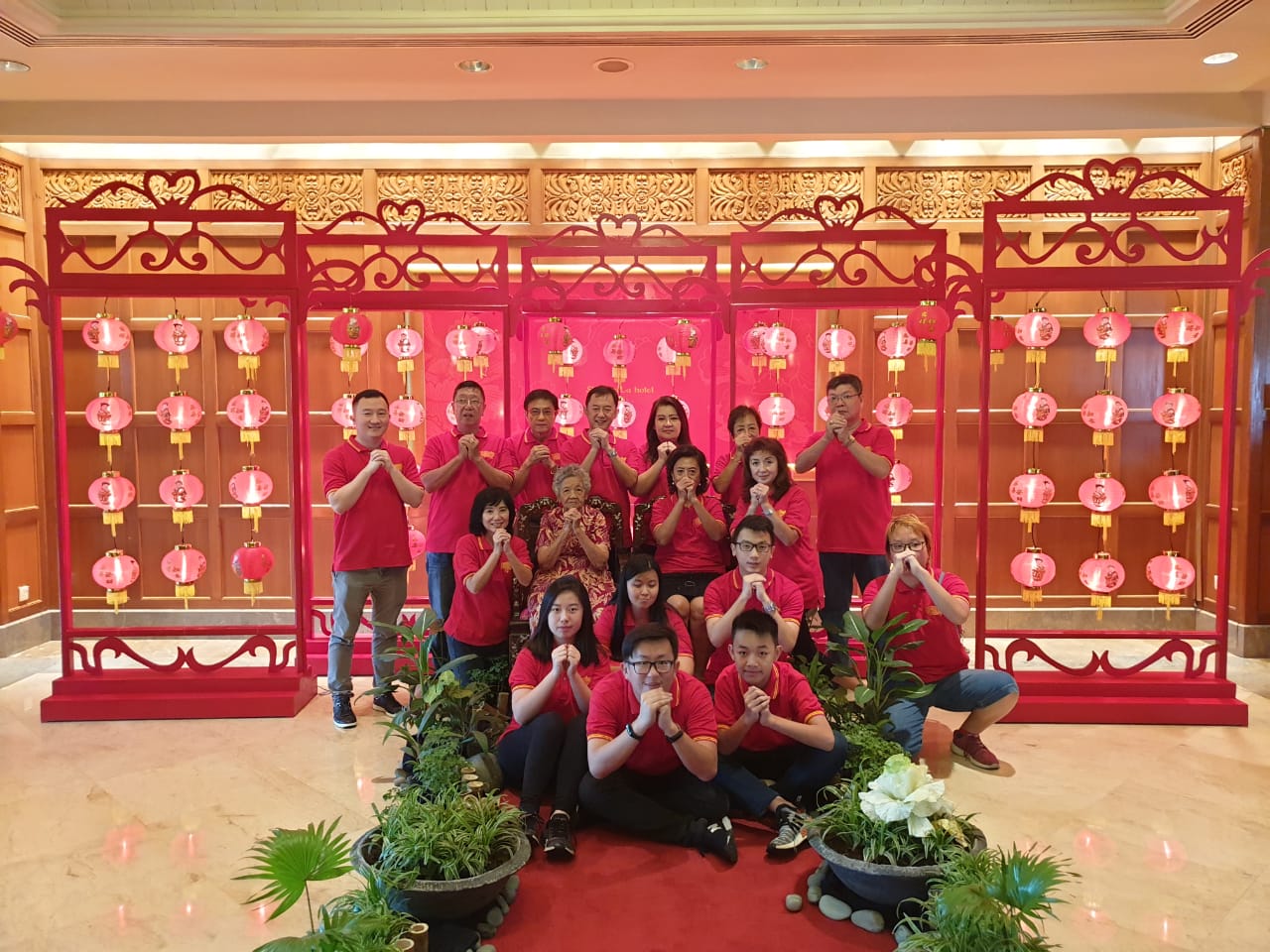 Sejumlah orang foro bersama dengan latar belakang hiasan dari budaya China