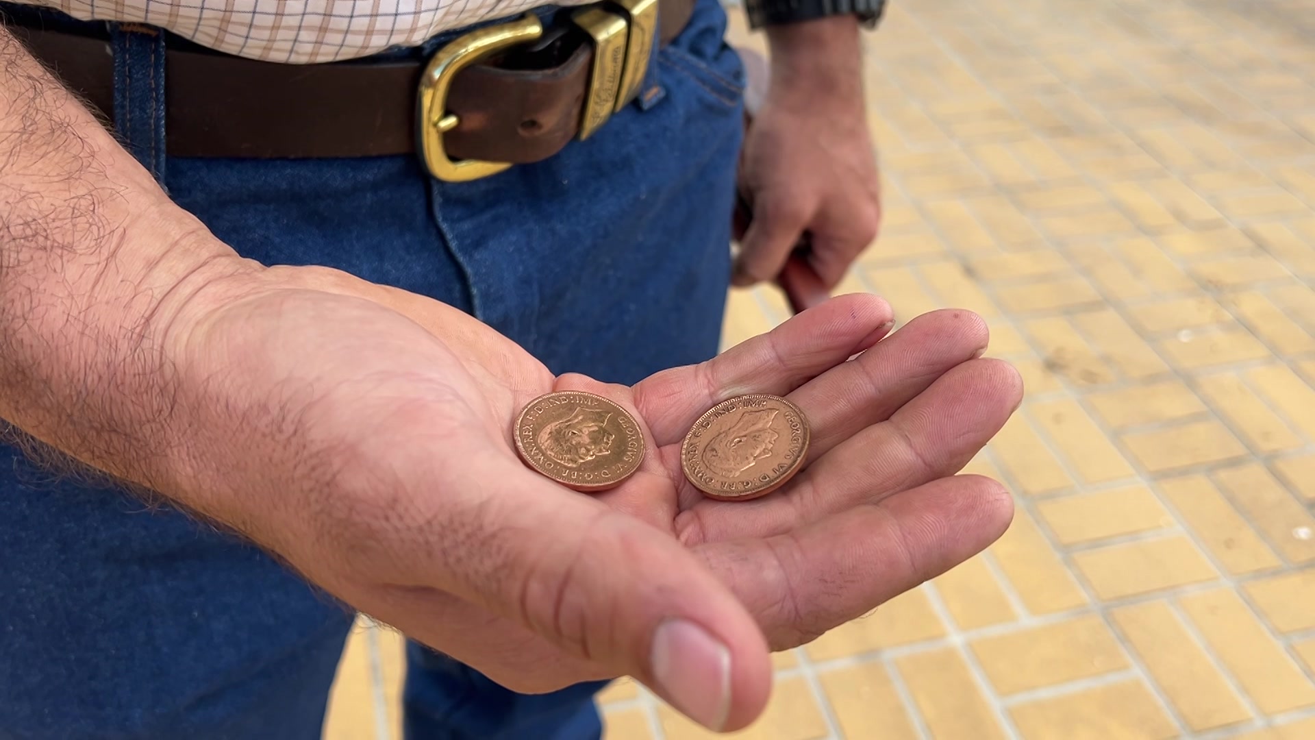 Una mano sostiene dos monedas de cobre.