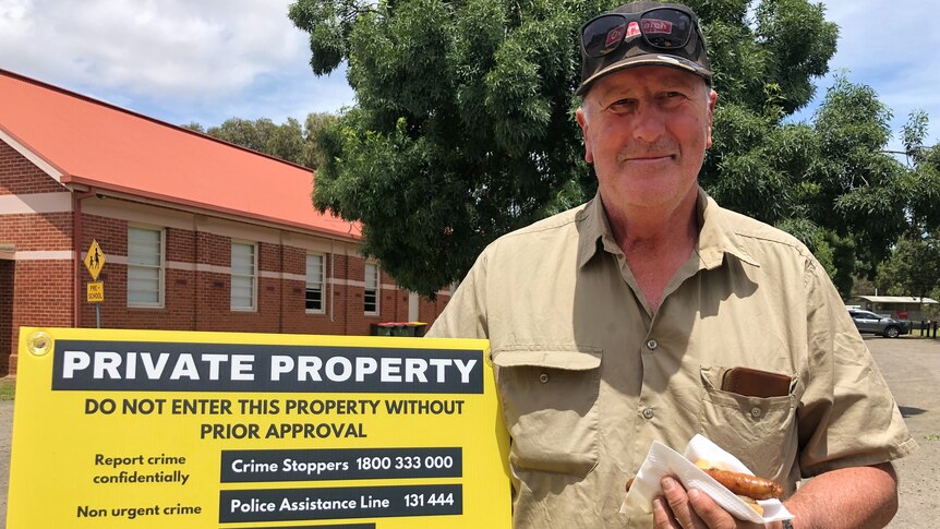 A man hold a sign that reads 'private property'