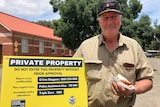 A man hold a sign that reads 'private property'