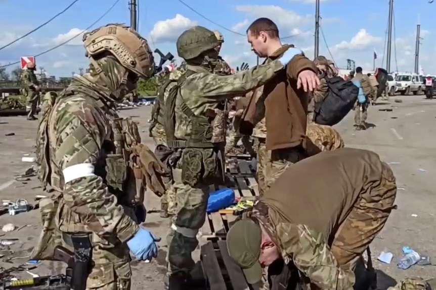 Russian servicemen frisk Ukrainian servicemen after they leaved the besieged Azovstal steel plant in Mariupol.