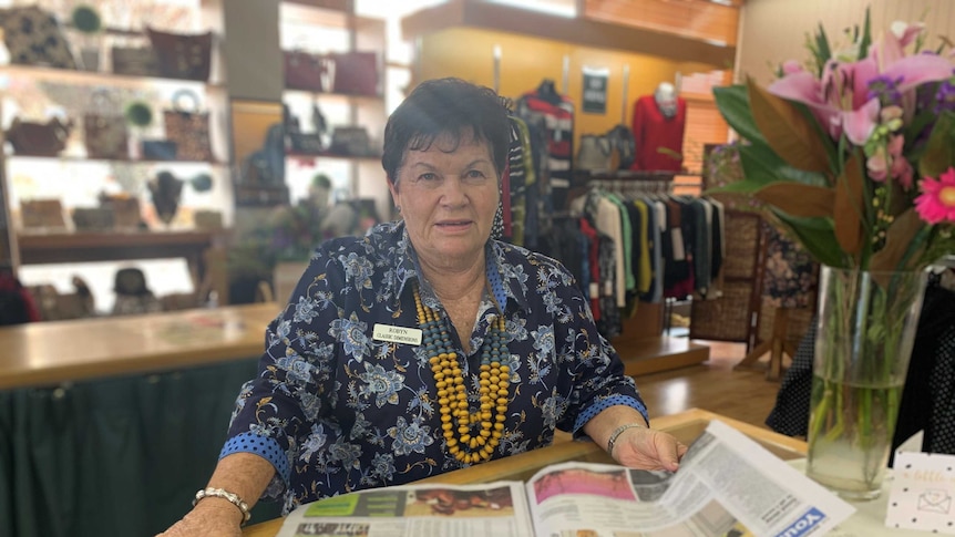 A middle-aged woman behind the counter of a newsagents shop