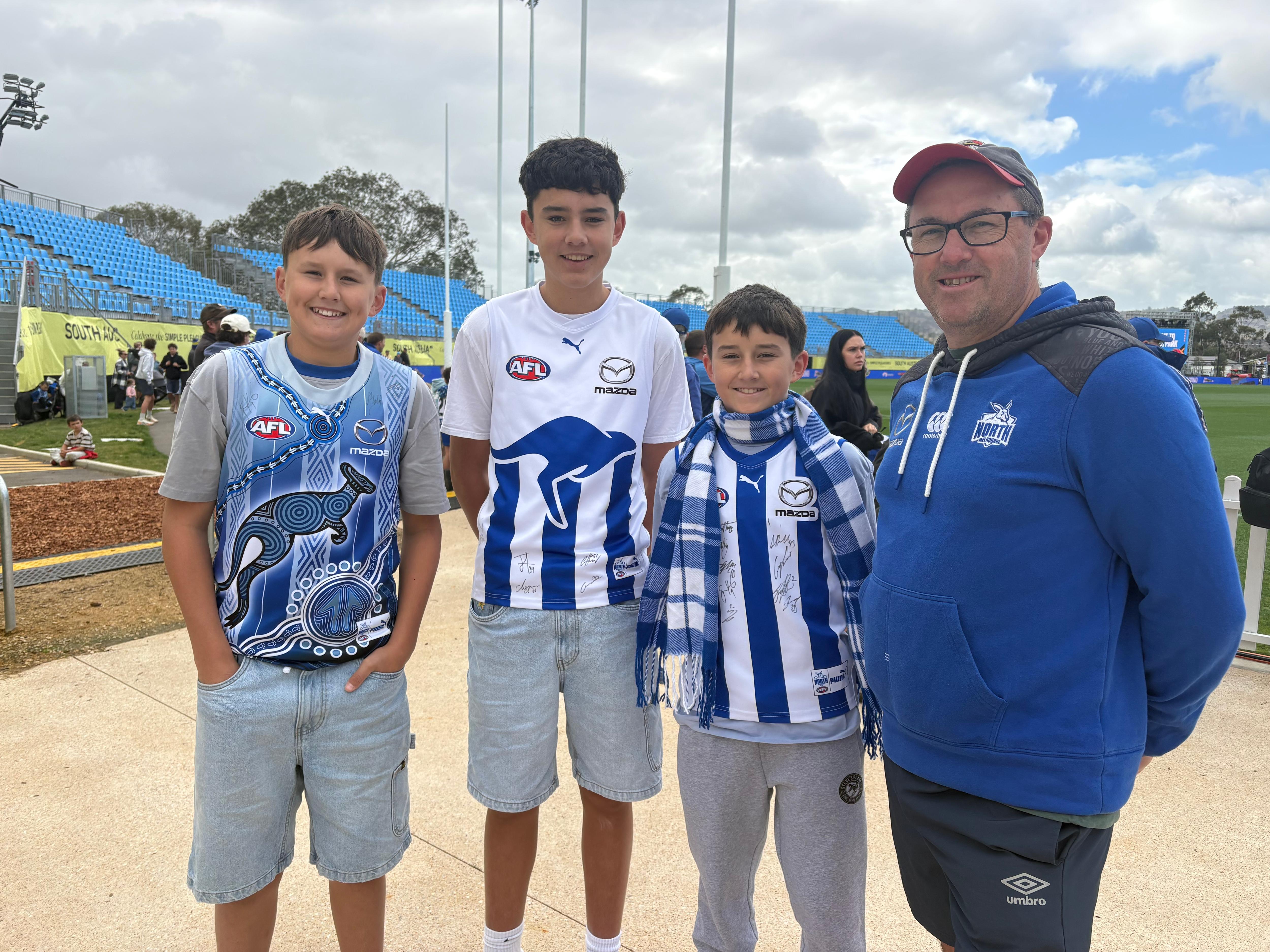 Três meninos e um homem vestindo roupas do Norte de Melbourne