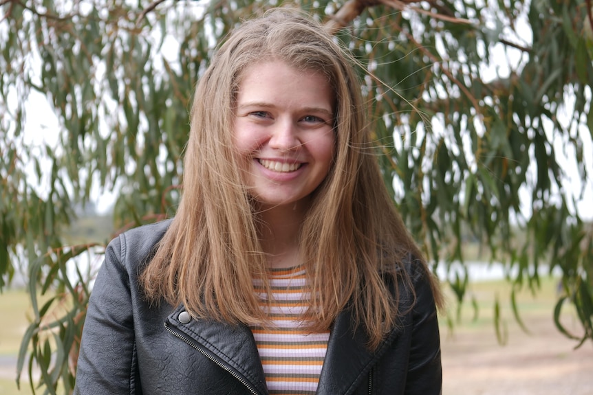 A girl with light brown hair smiles sweetly at the camera