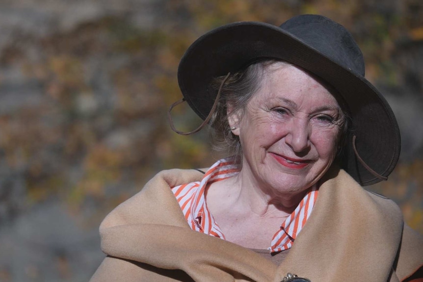 A smiling, well-dressed older lady wearing a hat