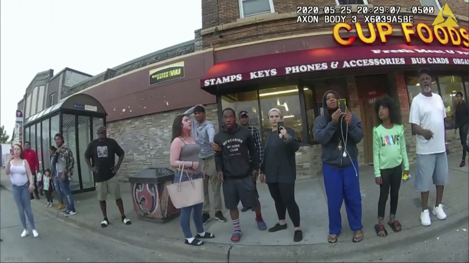 Bystanders filming police officer as he presses his knee on George Floyd's neck.