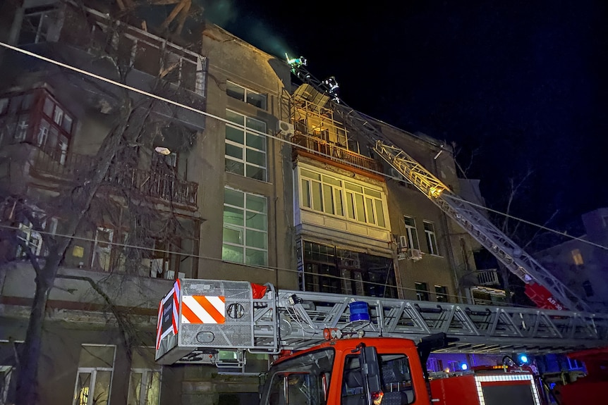 Ukrainian firefighters work at a site of an apartment building severely damaged by a Russian missile.