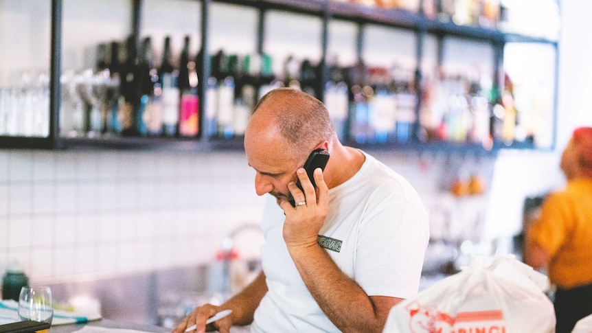 Man sits at restaurant counter talking on phone