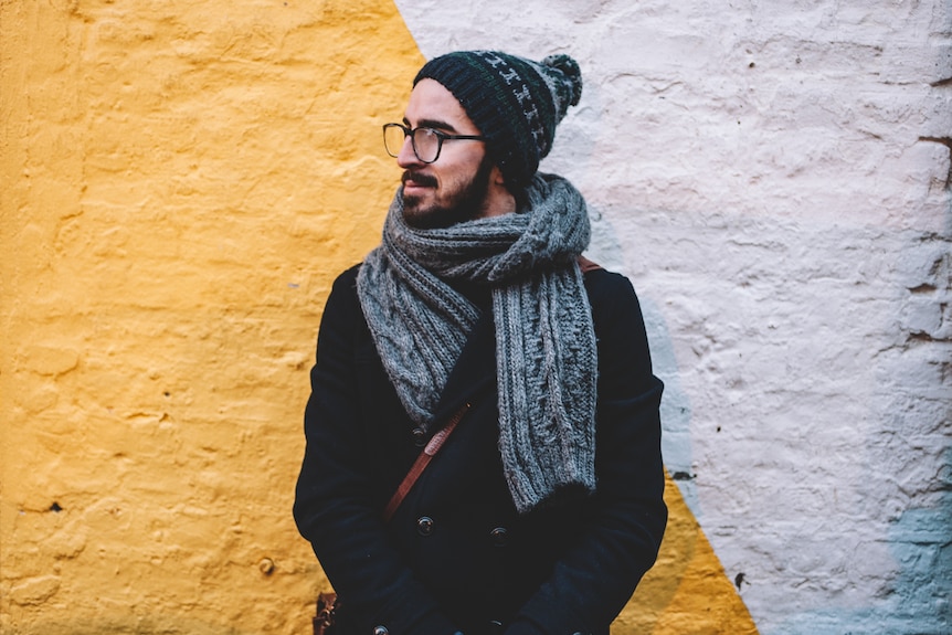 Man with glasses wearing winter clothes showing the necessity of moisturiser and sunscreen in this simple skincare routine.