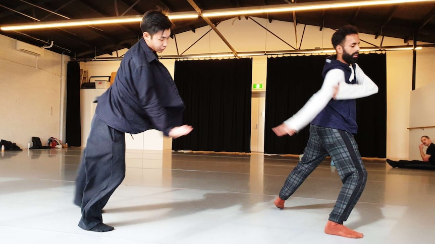 Aakash Odedra and Hu Shenyuan dance in unison in a rehearsal space.