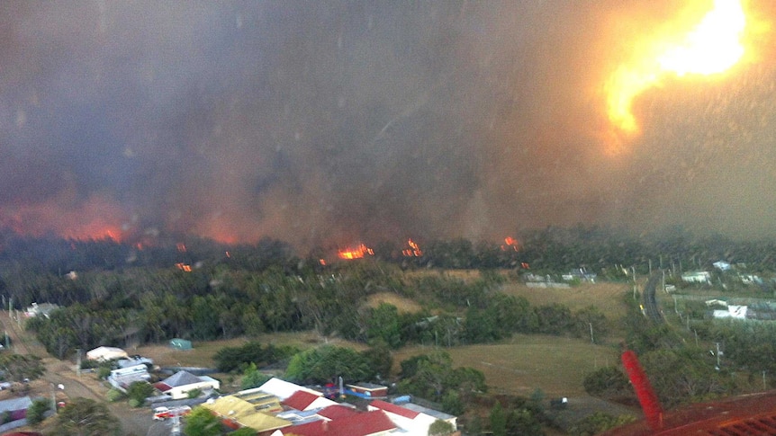 A helicopter flies ahead of the bushfire which wiped out scores of properties in Dunalley.