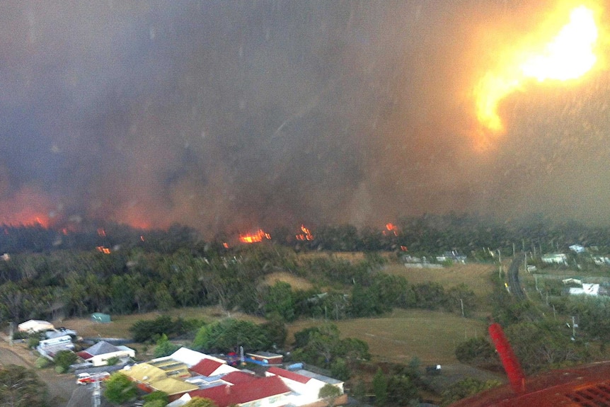 A helicopter flies ahead of the bushfire which wiped out scores of properties in Dunalley.