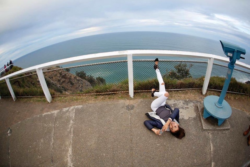 Mia Ayliffe-Chung lying on the ground near a lookout over the ocean, near Byron Bay Lighthouse.