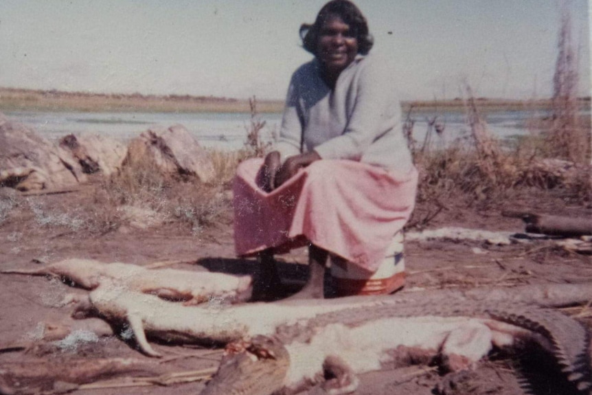 A woman sits with dead crocodiles.