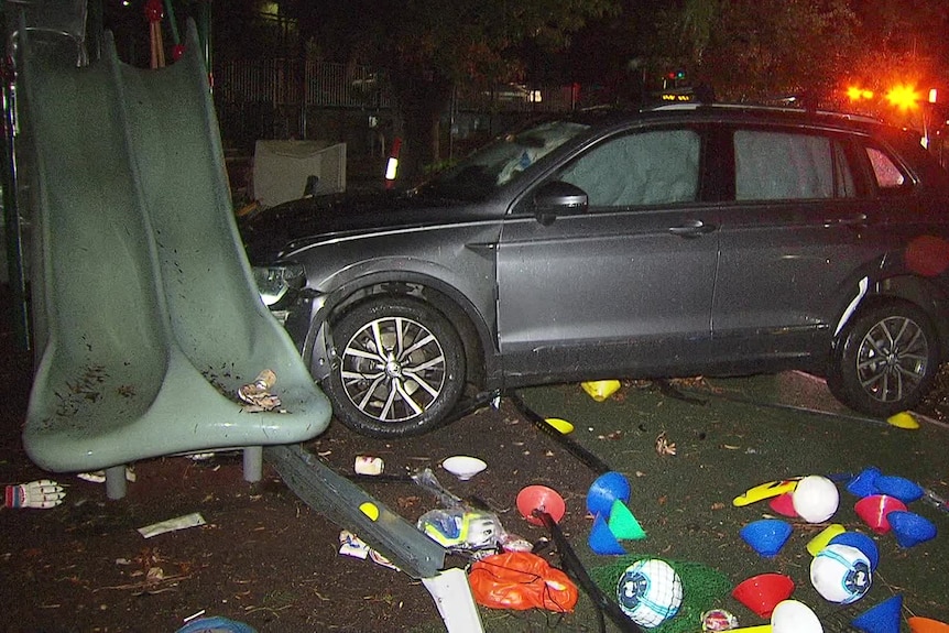A grey station wagon with airbags deployed crashed into a green slide, with sports equipment scattered