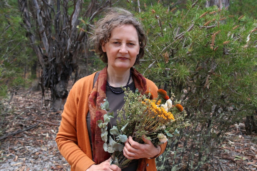 Wendy Elford holds a bunch of dried flowers at the memorial site.