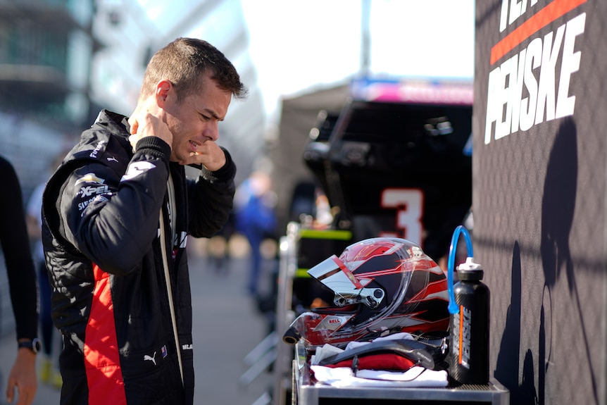 IndyCar driver Scott McLaughlin checks his driving gear, with his helmet and water bottle sitting in front of him.