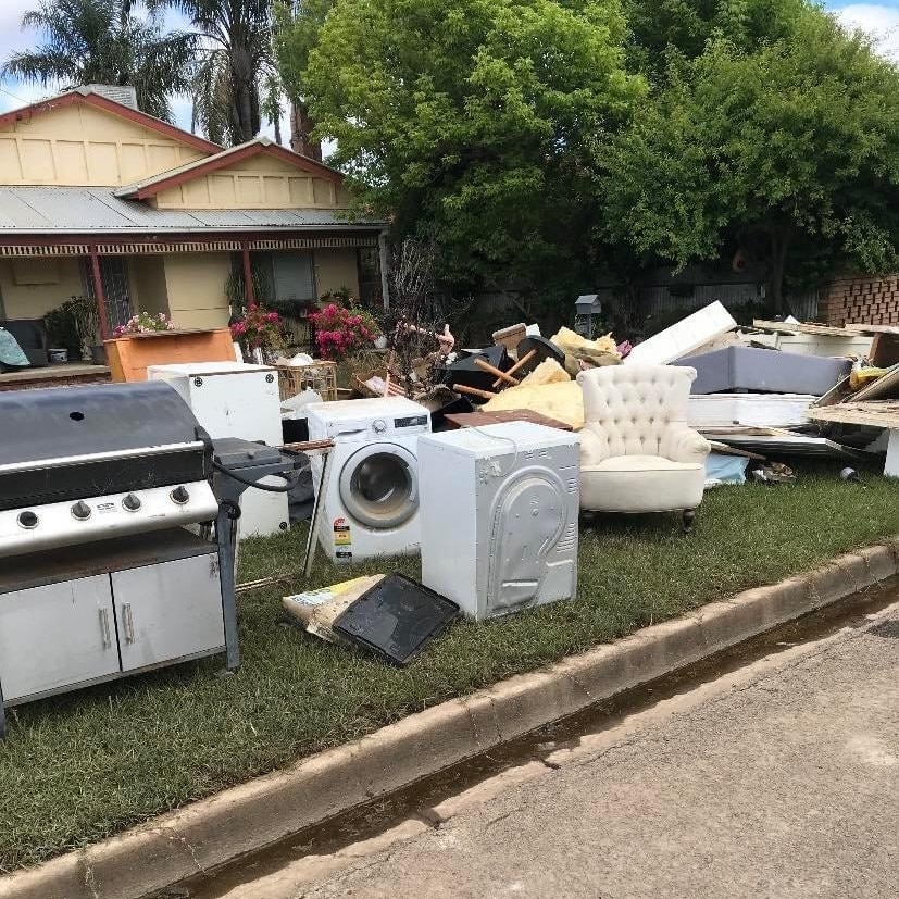 A house with appliances and furniture damaged by floods sitting on the lawn.