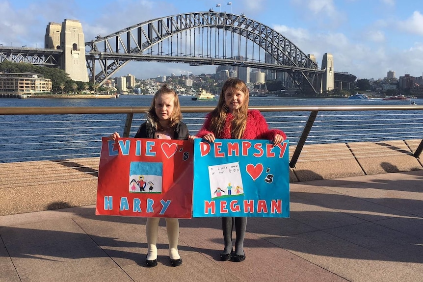 two young girls standing on harbour holding signs