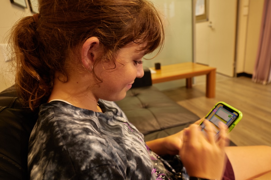 A teenage girl scrolls through her smartphone 