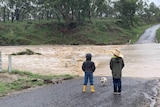 Two children look at a flooded road.