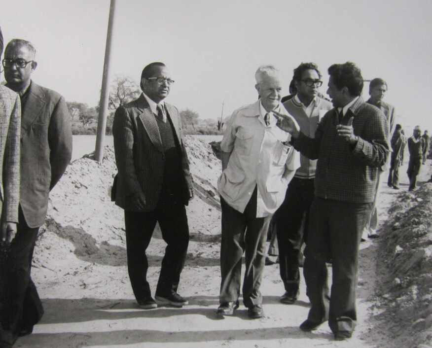 Historical photo of a man walking with agricultural scientists in India