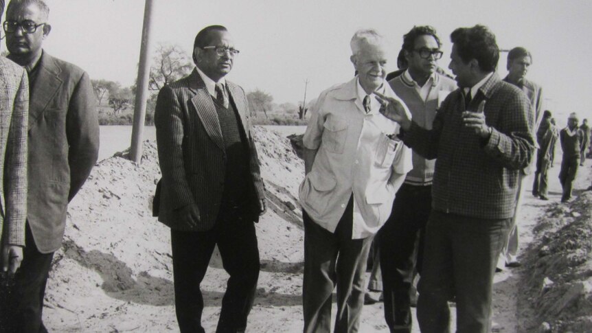 Historical photo of a man walking with agricultural scientists in India
