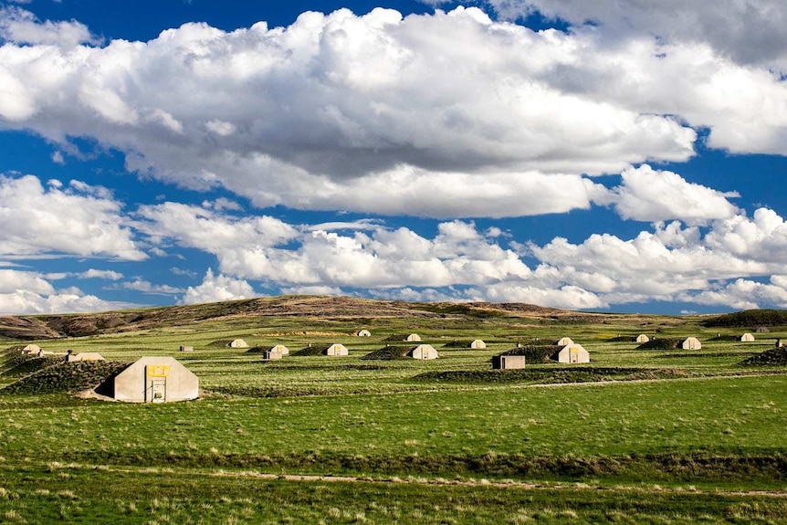 Concrete bunkers dot a green field.