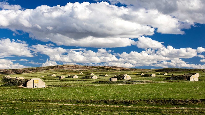 Concrete bunkers dot a green field.