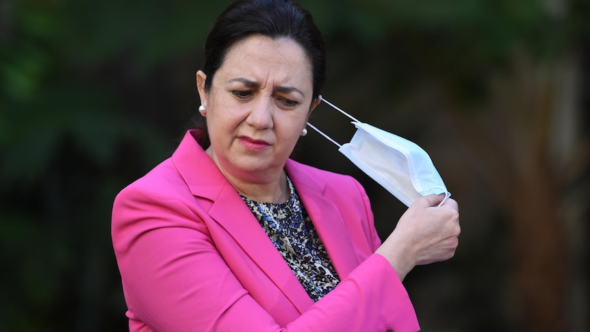  Queensland Premier Annastacia Palaszczuk in a pink suit pulls off her face mask.
