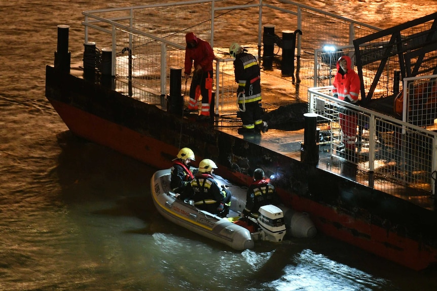 A boat with rescuers moors next to a landing dock in the Danube River.