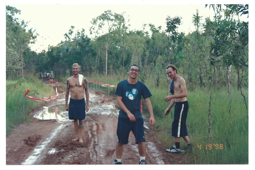 Three men stand in off road track which is covered with water