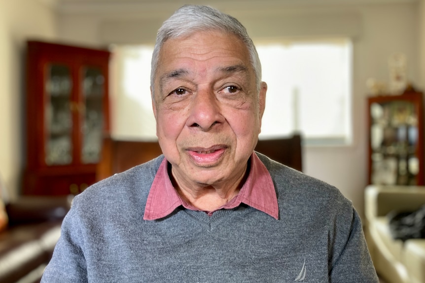 A man with white hair smiles at the camera.