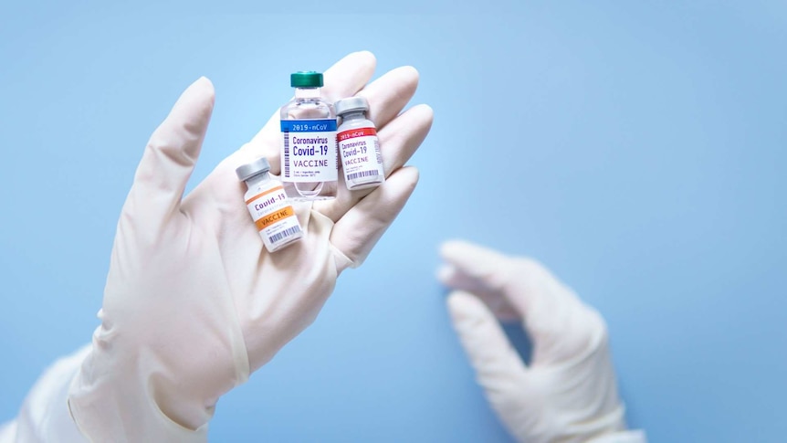 A white gloved hand hold three small labelled vials filled with clear liquid