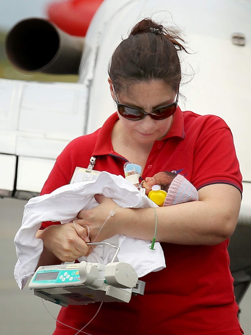 Midwife carrying a baby out of a plane.