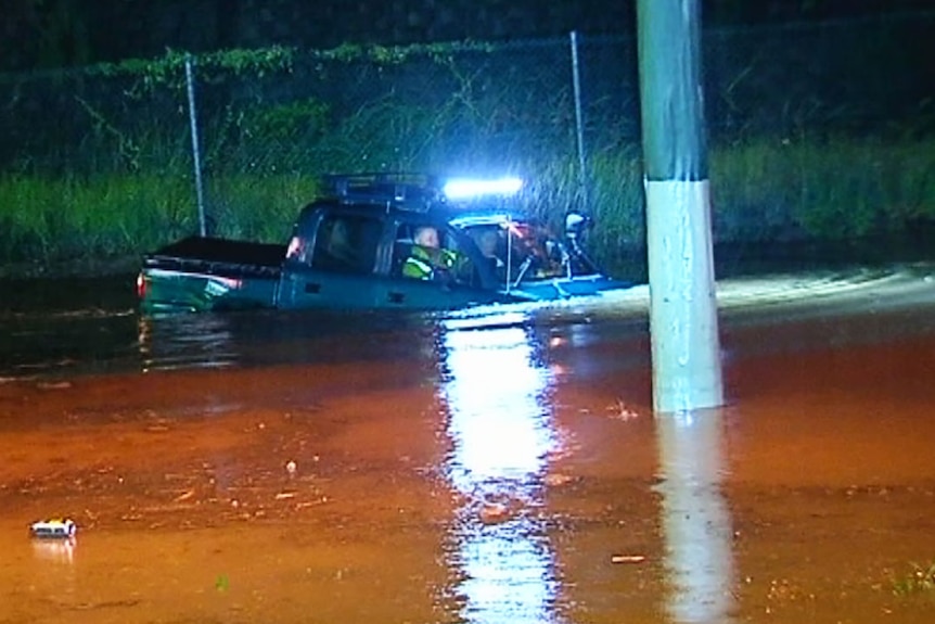 A man drives his four-wheel drive onto a closed road in flood at Helensvale.