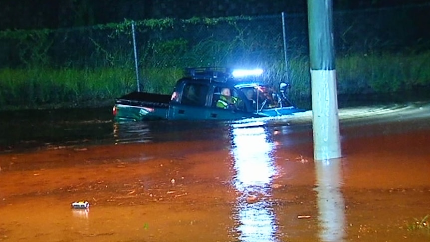 A man drives his four-wheel drive onto a closed road in flood at Helensvale.