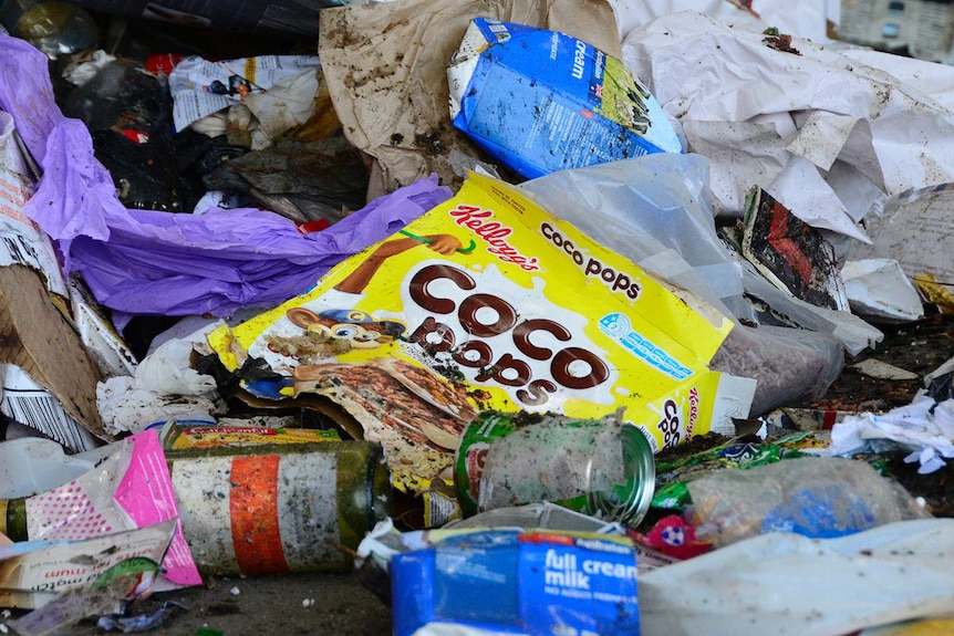 A pile of rubbish, dominated by an old Coco Pops cereal box.