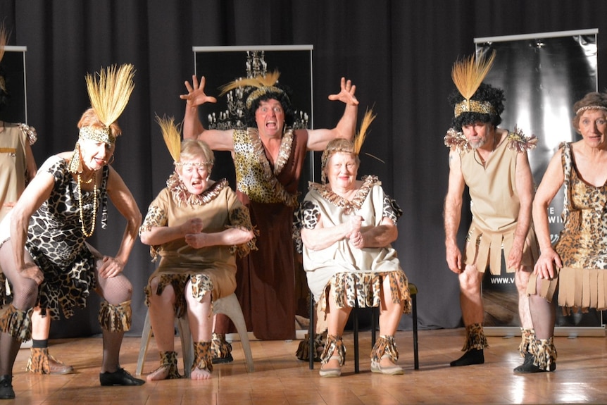 Performers in brown cosumes on stage, wearing Roman costumes.