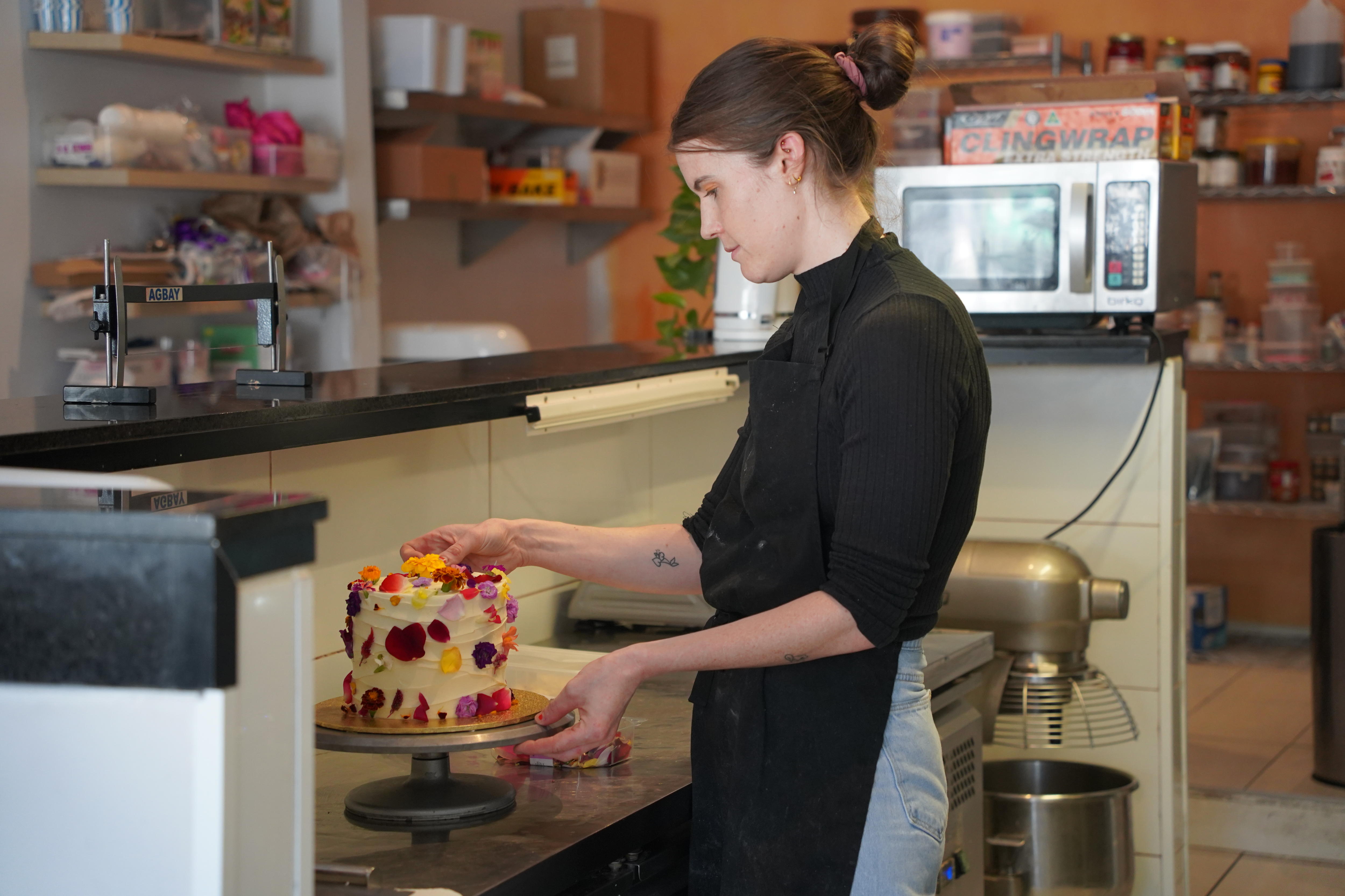 Un Cakemaker pone los toques finales en un pequeño pastel en una panadería