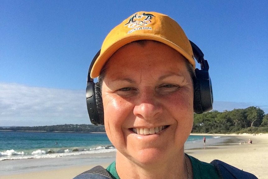 Julie Speight, a former Olympic cyclist, standing on a beach wearing an Australian Olympic team hat.