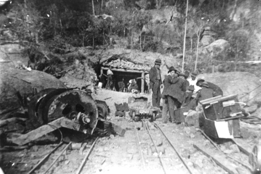 A black and white photo of debries scattered around a mine entrance .