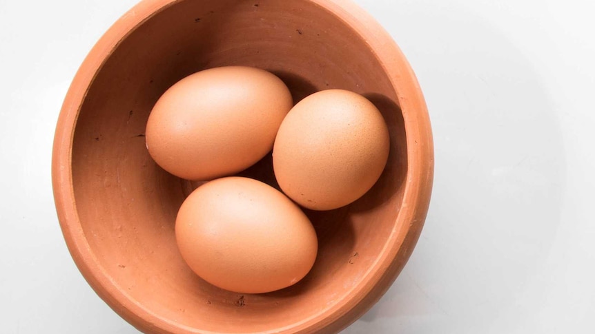 Three eggs in a terracotta coloured bowl.