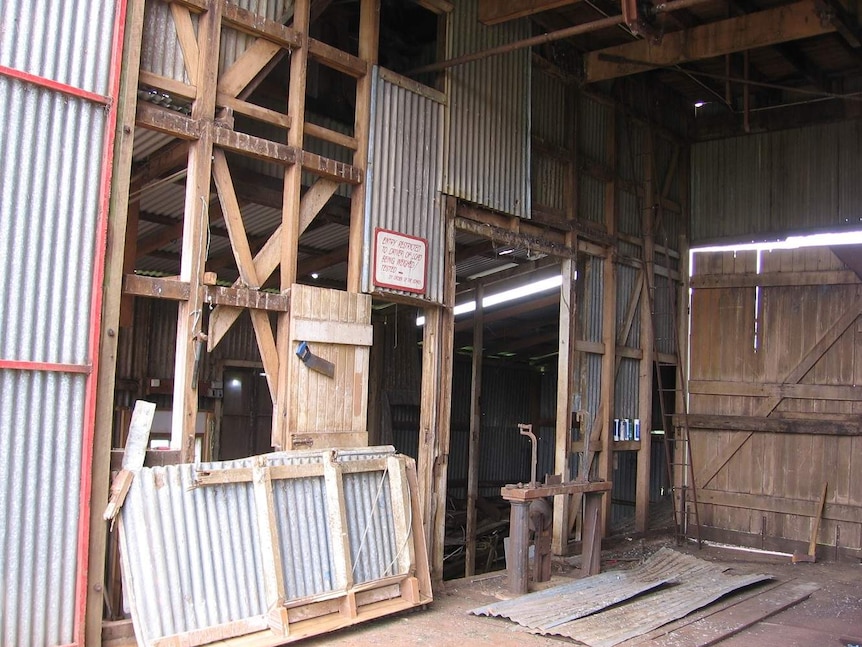 A view inside an old tin shed, showing missing pieces of iron walls and doors as well as bird poo.
