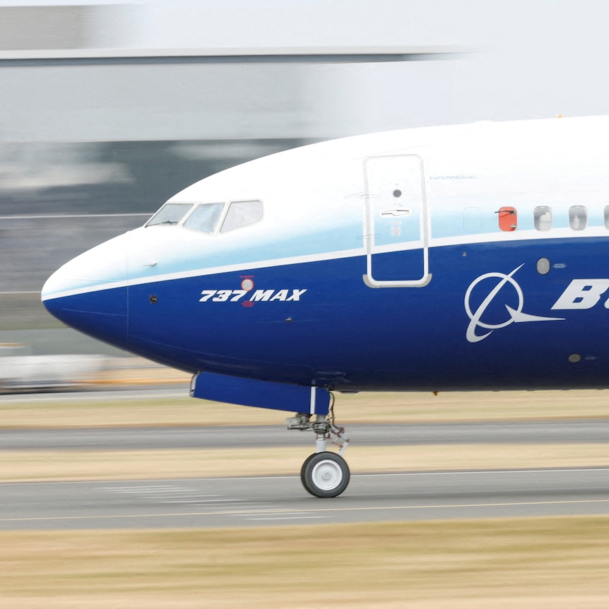 A white and blue plane with the word 'BOEING' and the markings '737 MAX' written on its side.