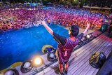 A person on stage gestures to a huge crowd of people in a pool in Wuhan, during a music festival.